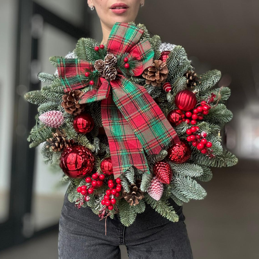 Coroniță „Christmas Joy” cu fundă roșu-verde, ținută în mâini